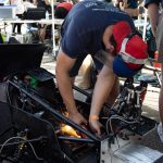 A student grinding metal on the car with sparks flying. 