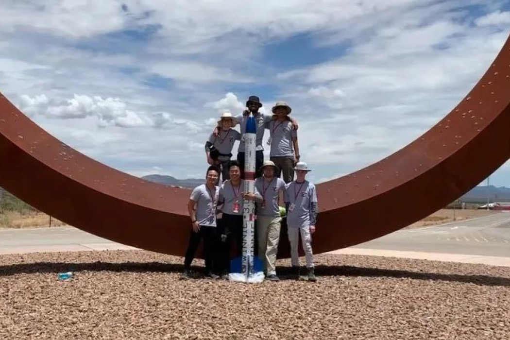 The U M S A T S rocketry team standing in front of their rocket in New Mexico.