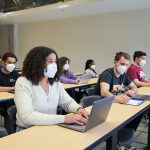 Students wearing KN95 masks and taking notes on laptops and with pencil and paper in a classroom. // Photo from David Lipnowski