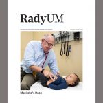 Cover of Summer 2022 issue of RadyUM magazine, showing Dr. Brian Postl giving a checkup to a baby.