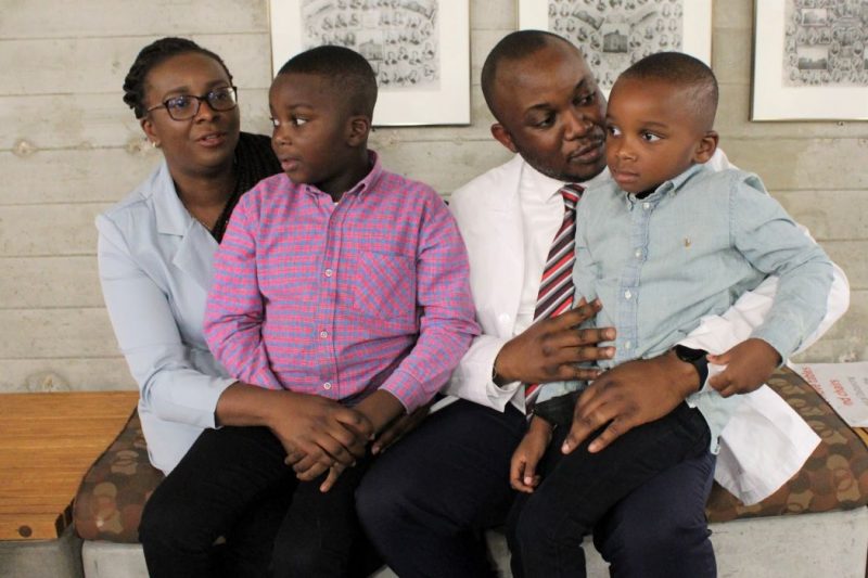 International Dentist Degree Program student Deji Omotayo sits with his wife and two young sons after the Opening Assembly.