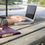 A student works on a laptop at a picnic table.