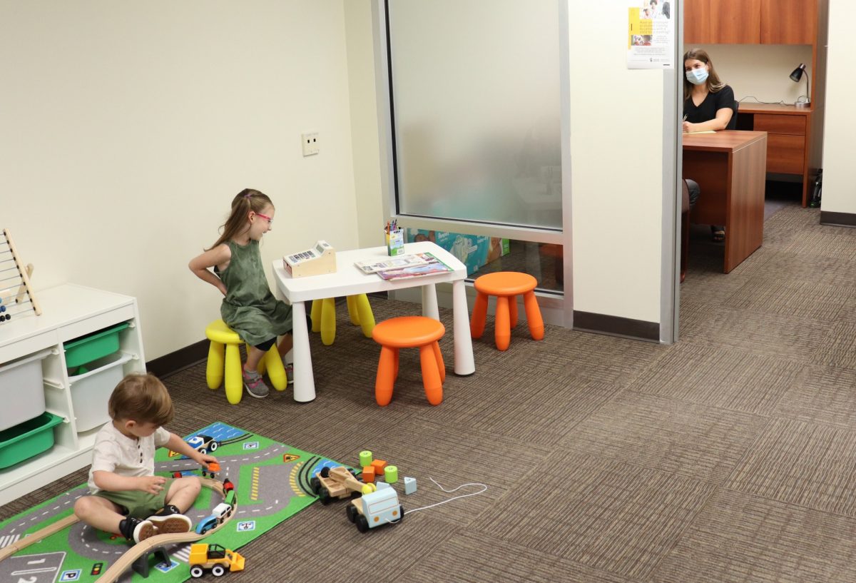 two kids play with toys while an open door meeting takes place