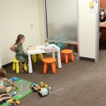 two kids play with toys while an open door meeting takes place