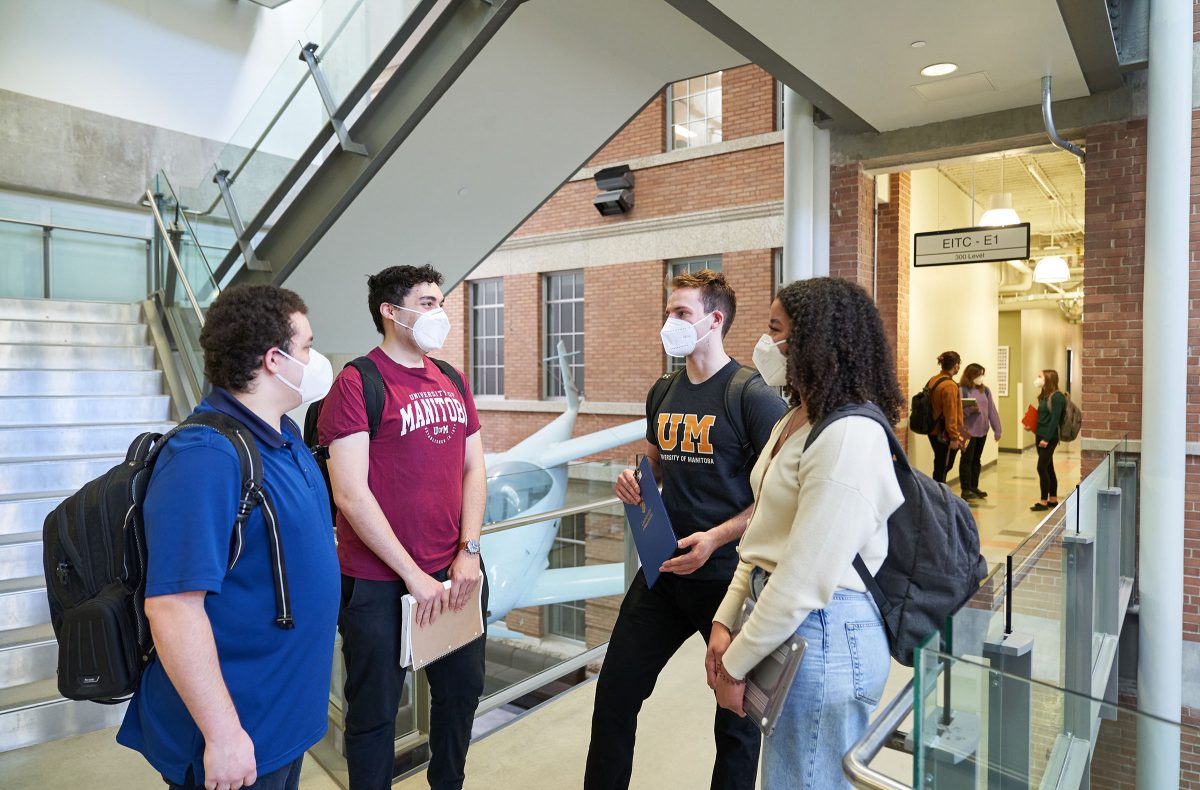 A group of students in masks talking in a hallway in EITC.