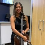 Law student Edvanny Silva Burns holding cello backstage at Michael Buble concert