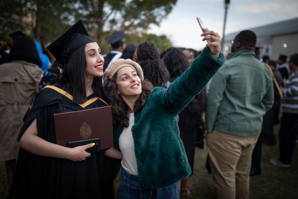 A grad poses with a friend for a selfie during a Convocation after party
