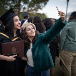 A grad poses with a friend for a selfie during a Convocation after party