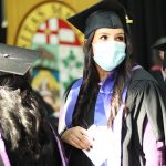 Christina Keeper, dressed in cap and gown, stands in a line with the University of anitoba