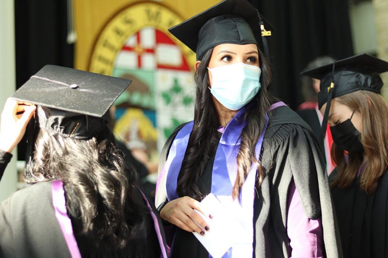Christina Keeper, dressed in cap and gown, stands in a line with the University of anitoba