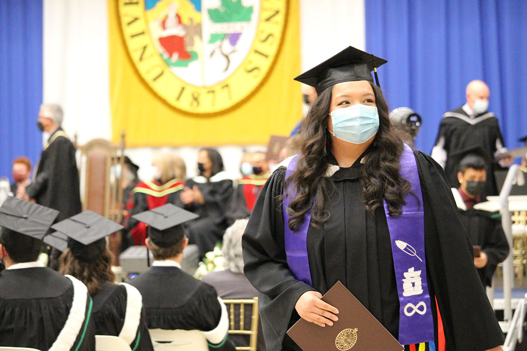 A female Indigenous student walks proudly after receiving her degree at convocation.