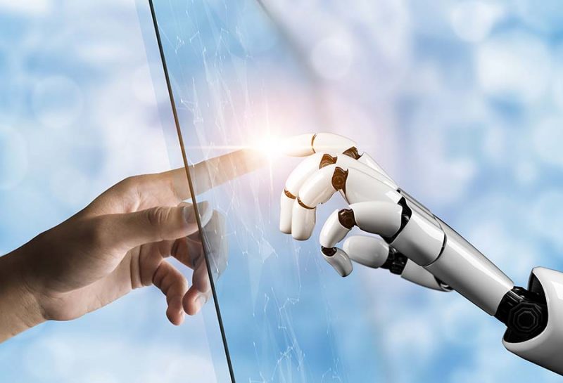 Photo of a human hand touching a robot hand.