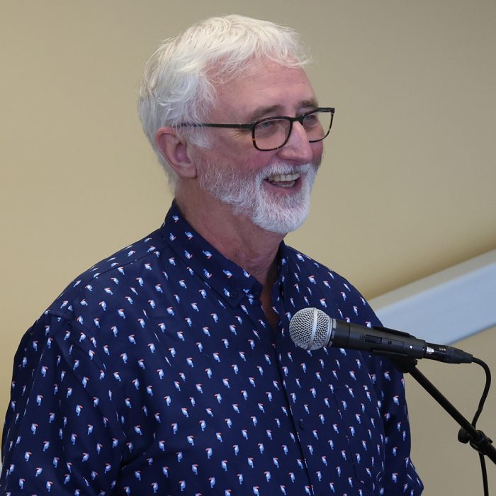 Don Petkau smiling while speaking at a podium with a microphone. 