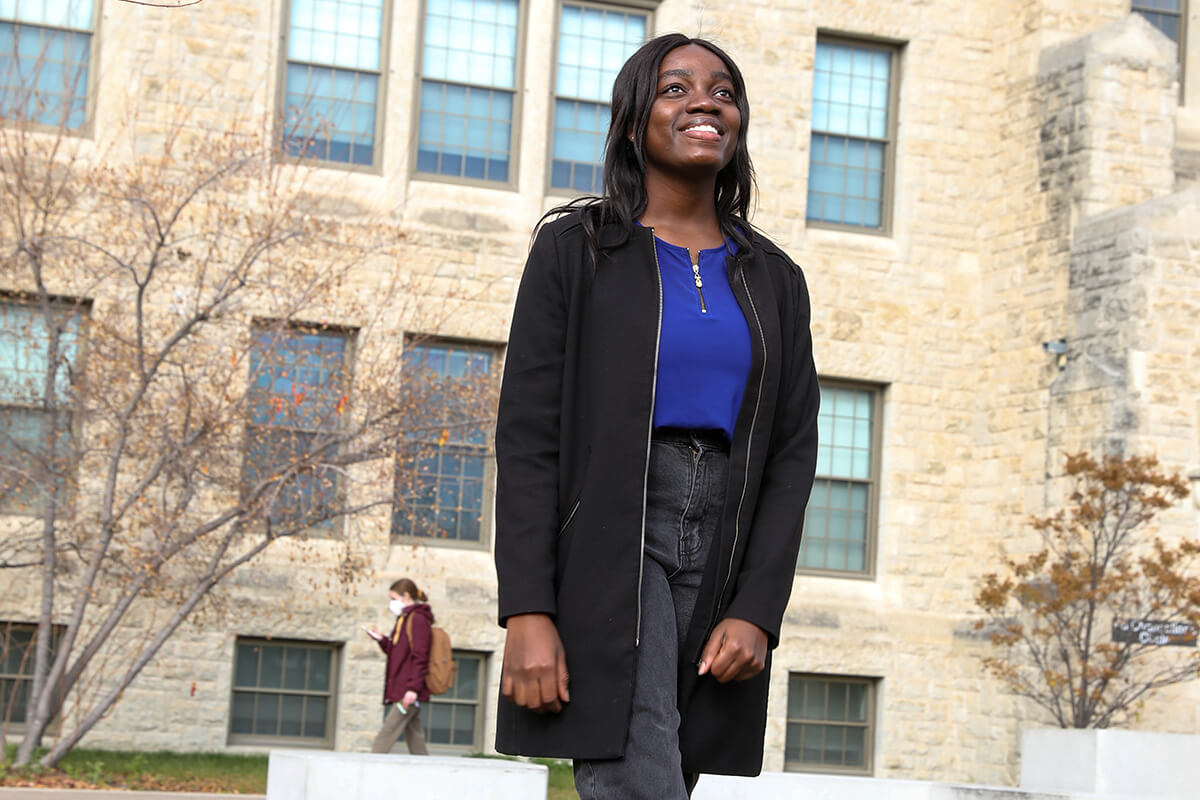 Student stands in front of admin building.