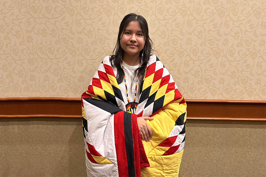 Indigenous student with star blanket and medallion.