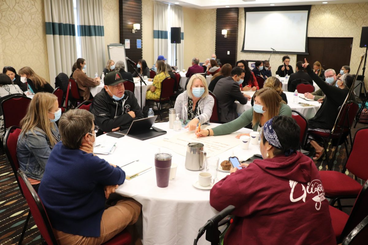 University and community representatives work at tables in a conference room.