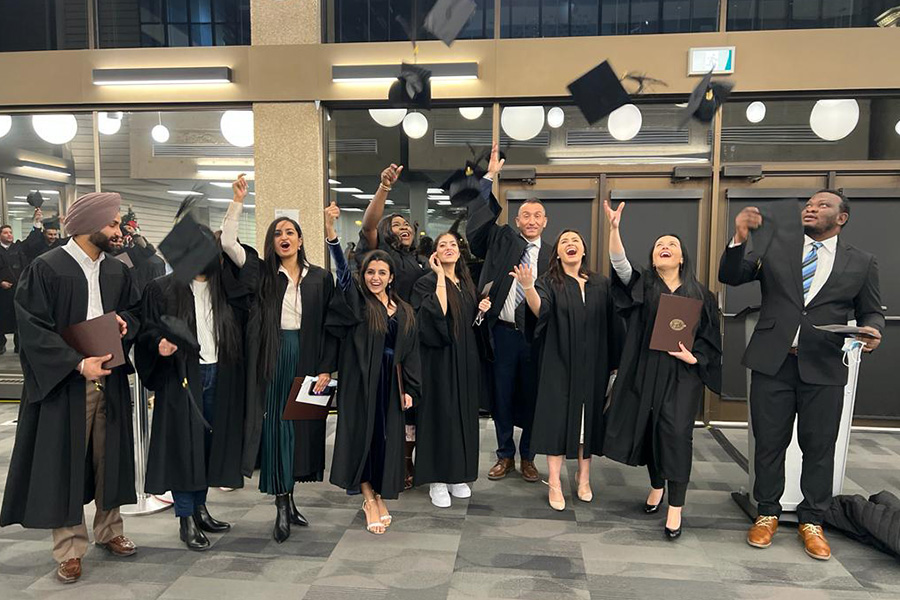 Photo of graduates in gowns tossing caps in the air.