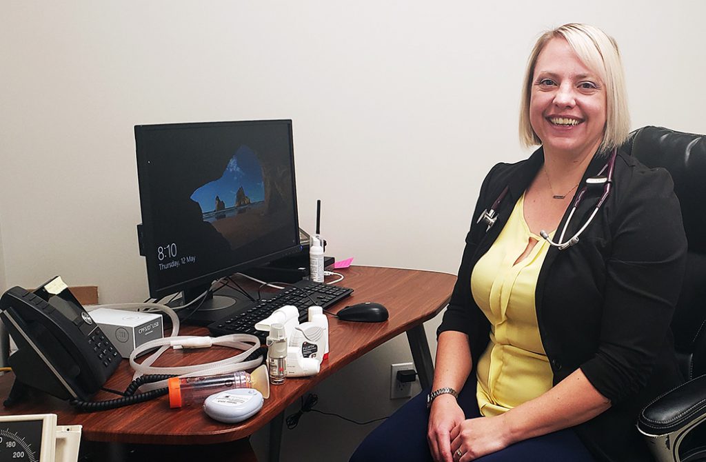 Karen McElroy sits at her desk with several respiratory therapy devices.