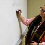 Dr. Laura MacDonald writes on a whiteboard.