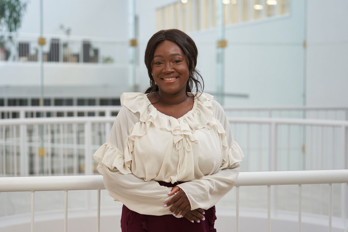 Carine Bado is in a white shirt standing next to a white railing.