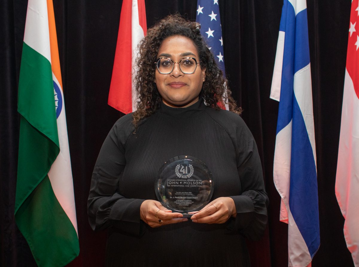 Judy Jayasuriya Standing with a Trophy in front of a set of five flags