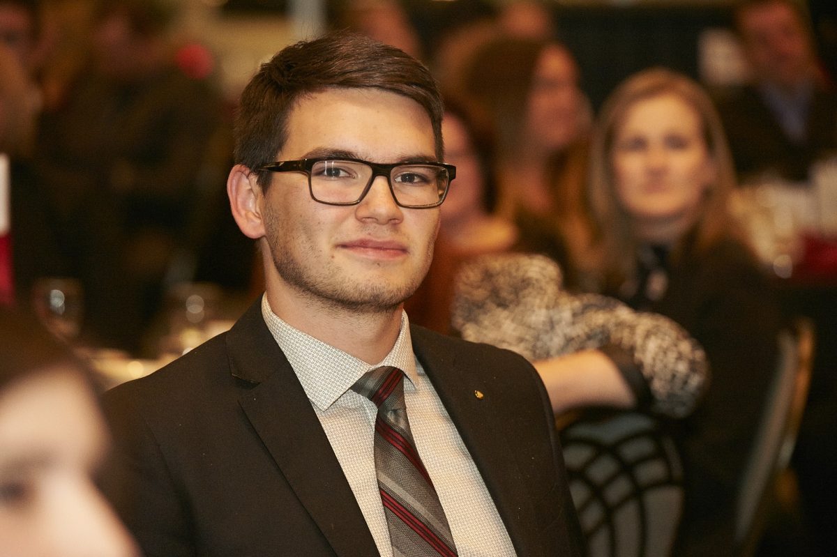 Man with glasses and tie sits at a table at an event