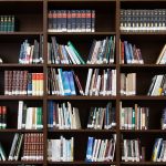 A library book shelf filled with books of various sizes, colours and widths.