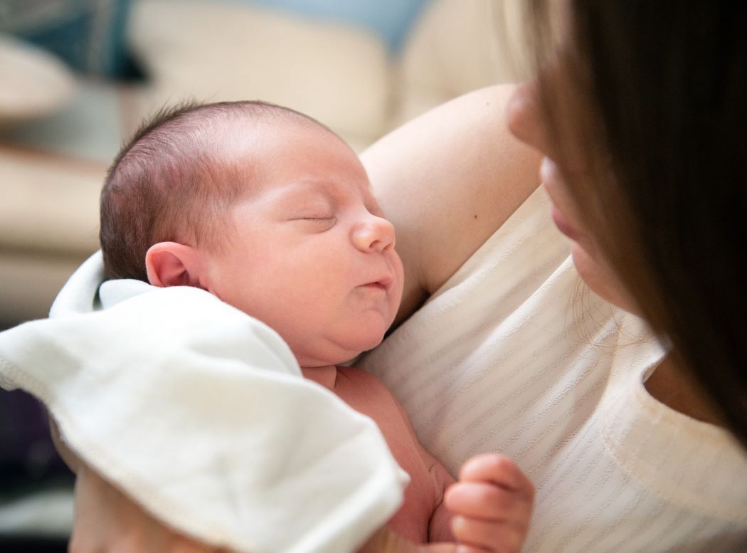 Closeup of a mother cradling a newborn baby.