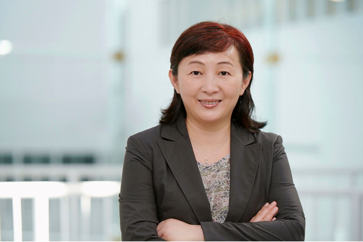 Lady standing with arms crossed in suit jacket.