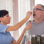 A health-care worker drops CBD oil on a patient's tongue.