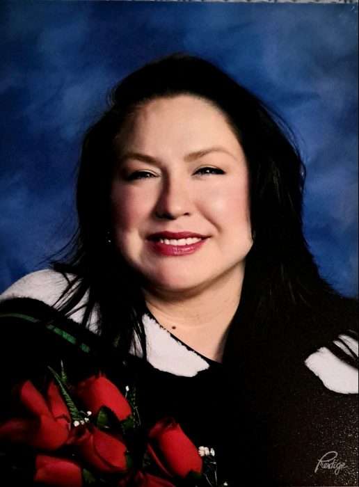 Graduation photo of woman in gown with red roses.