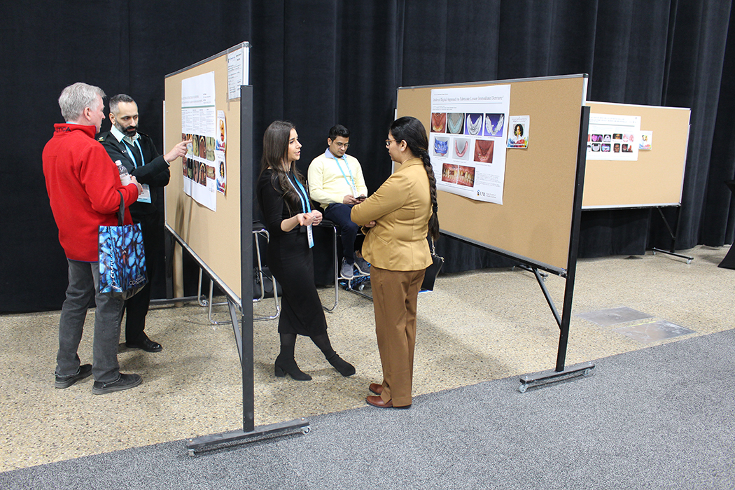 Small groups of people look at research posters at a Research Day event.