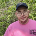 student pictured outdoors, wearing pink t-shirt and a hat with bisons logo