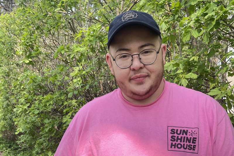 student pictured outdoors, wearing pink t-shirt and a hat with bisons logo