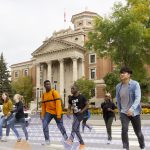 Students walk across the crosswalk in front of the administration building.
