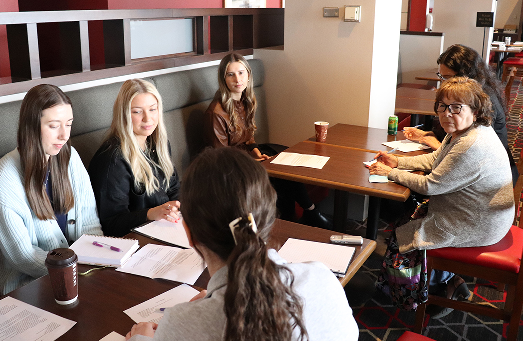 A group of female students in a discussion with Indigenous health leaders at a table.