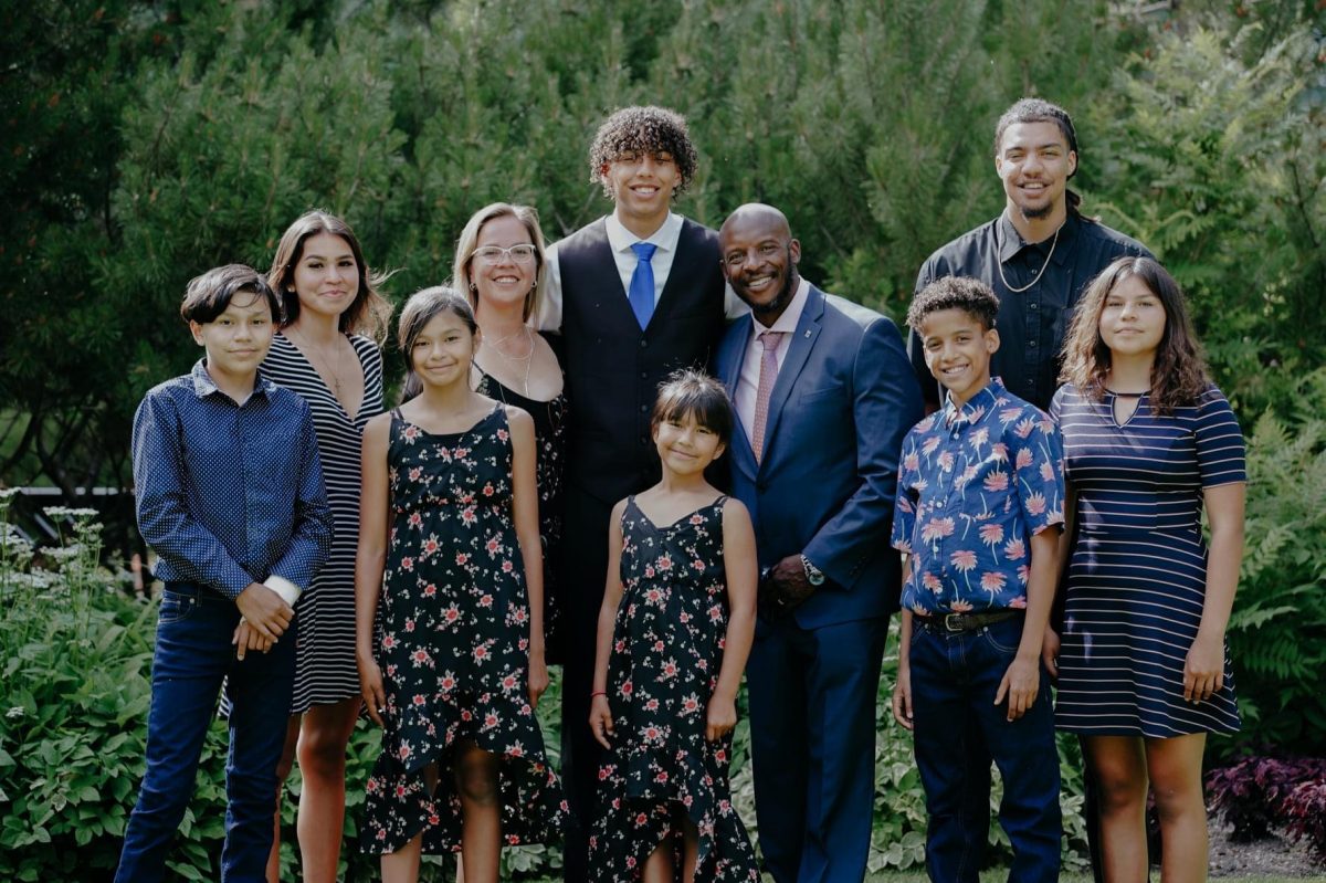 Photo of a family group of 10 people smiling by trees.