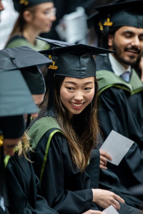 A pharmacy student is wearing a graduation cap and gown. 