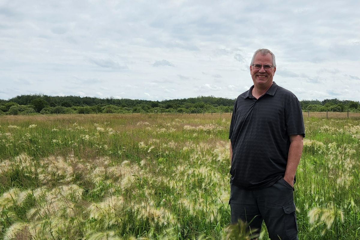 man stands in a field smiling