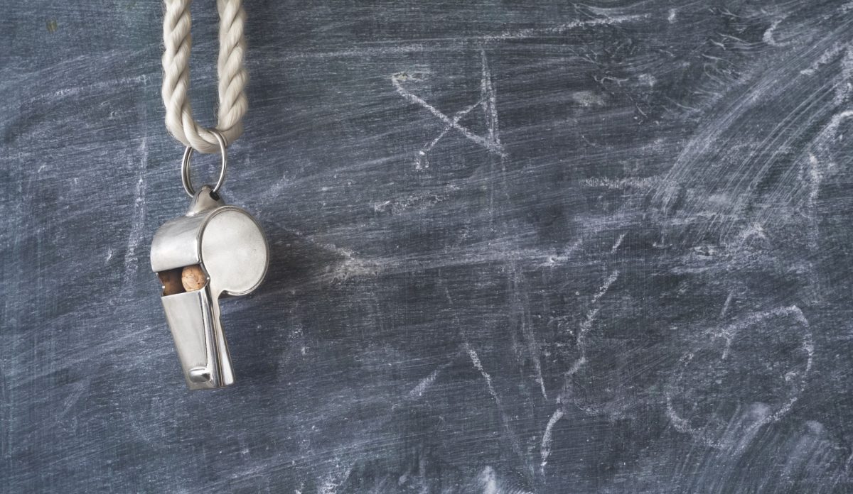 A coach's whistle hangs on a chalkboard.