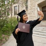 A UM grad proudly takes a selfie with her parchment