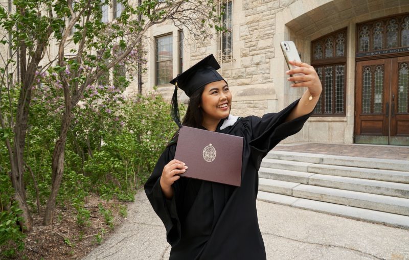 A UM grad proudly takes a selfie with her parchment