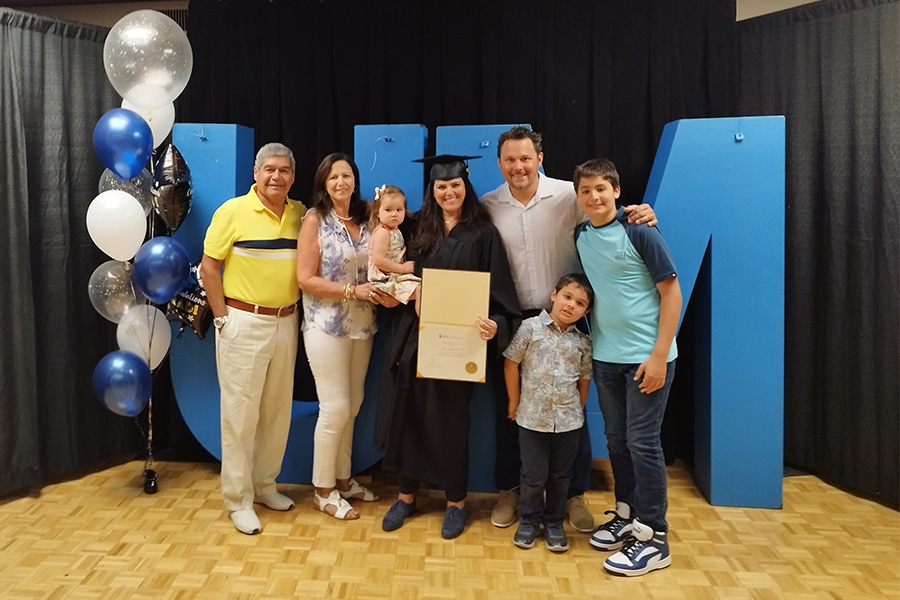 Photo of a graduate with her certificate and her family.