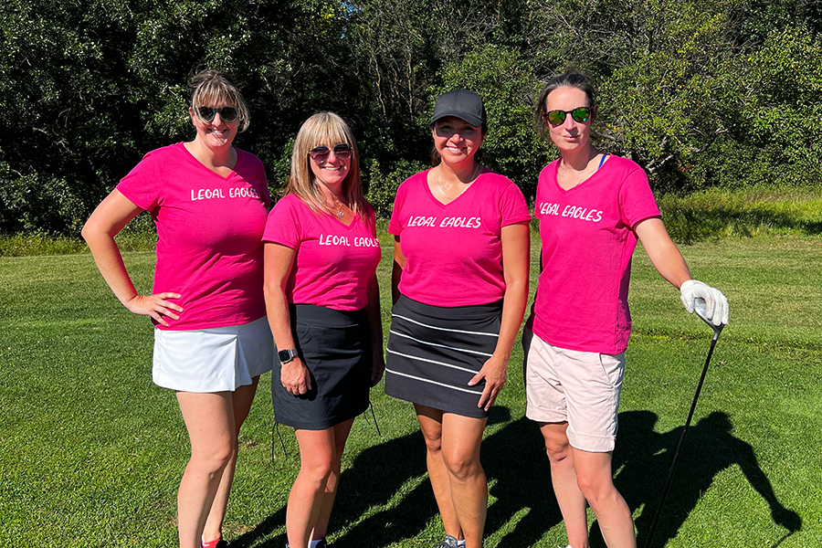 Group of faculty and staff members posing for photo at golf course