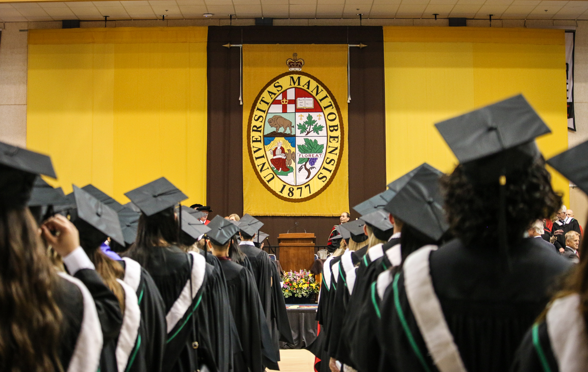 group of graduates photographed from behind featuring the university of manitoba crest