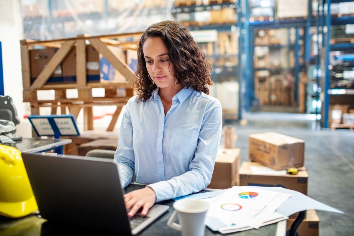 Woman looking busy working on laptop at a distribution warehouse.