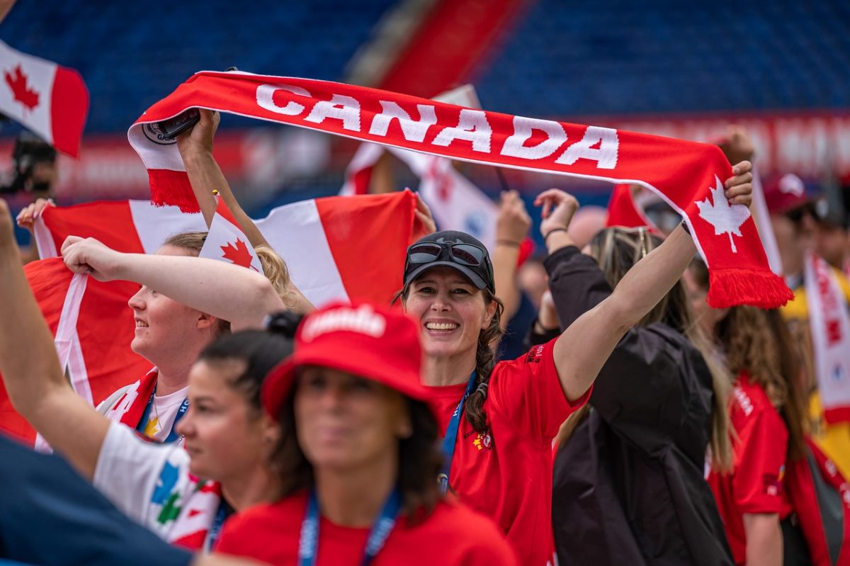 Canadian athletes waving banners coming into a stadium at the World Police and Fire Games opening ceremonies in Rotterdam in summer 2022