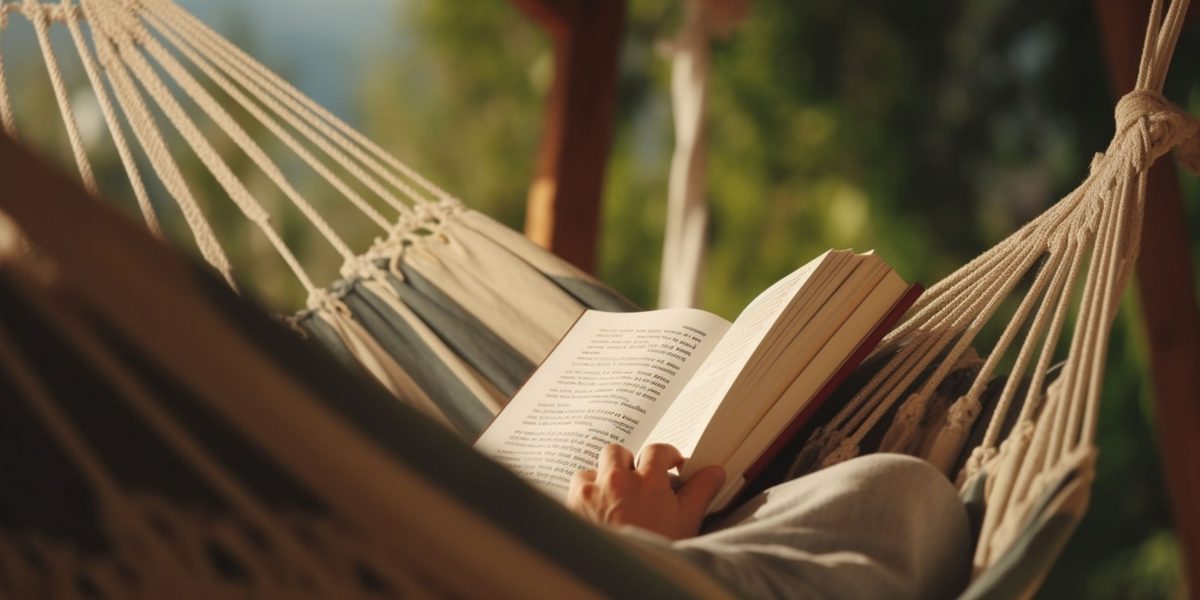 Person laying in a hammock, reading a book. Their face is not visible.