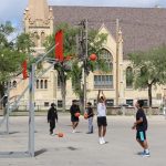 Six basketball players shoot hoops on two baskets.