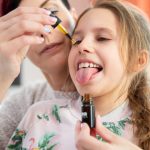 Mother drops CBD oil on daughter's tongue.